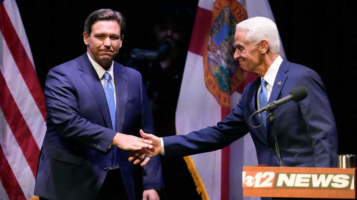 El gobernador republicano de Florida, Ron DeSantis (izq.) le da la mano al exgobernador Charlie Crist, demócrata de Florida, al comienzo de su debate televisado en el Teatro Sunrise en Fort Pierce, Florida, el lunes 24 de octubre de 2022.