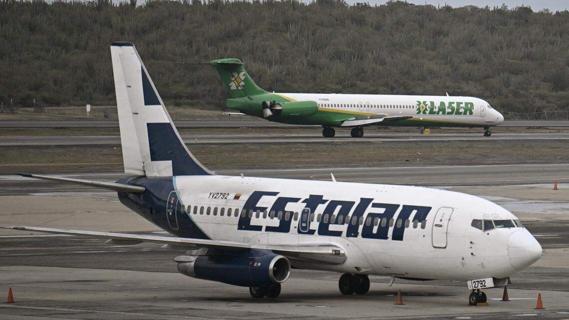 A Laser Airlines plane lands as an Estelar Airlines plane taxis at Simon Bolivar International Airport in Maiquetia, Venezuela on November 24, 2025. Six airlines cancelled flights to Venezuela on November 22, 2025, an industry group said, after the US aviation regulator warned of dangers from "heightened military activity" amid a major buildup of American forces in the region. (Photo by Juan BARRETO / AFP via Getty Images)