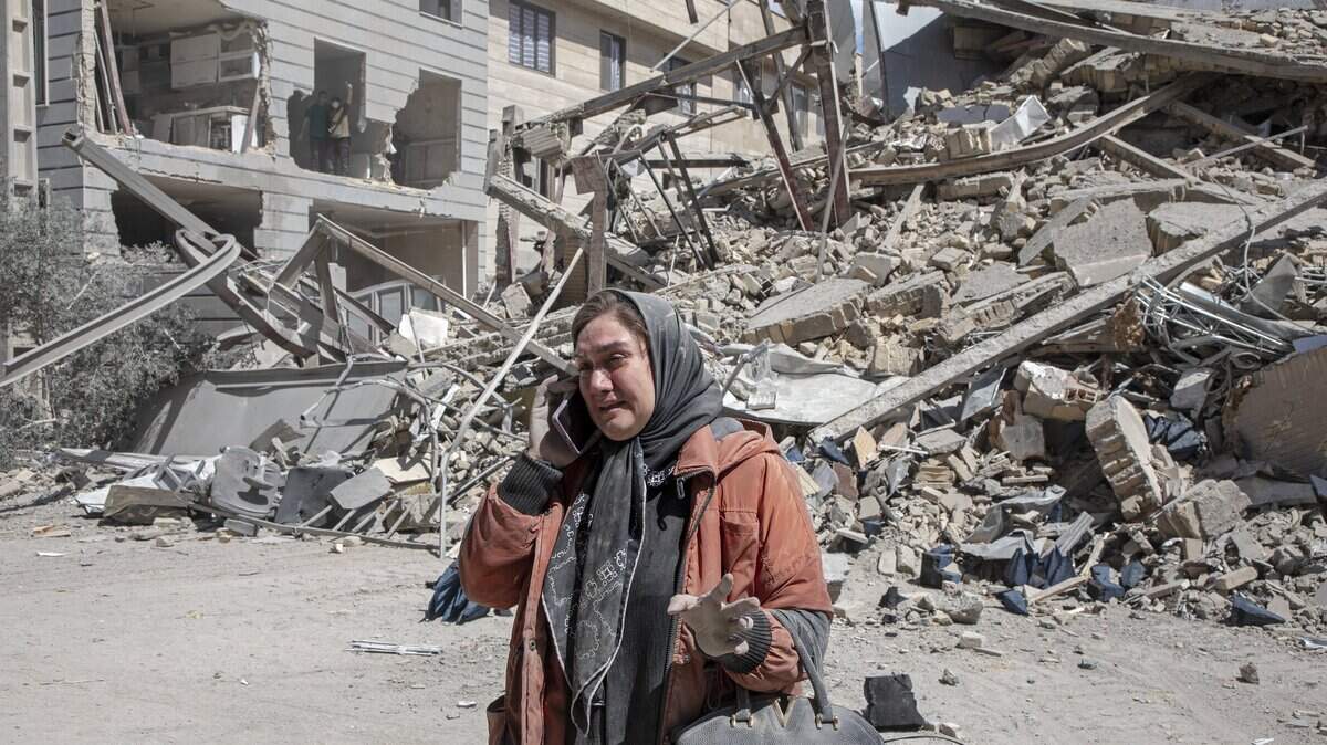 Una mujer llora mientras habla por teléfono cerca de un edificio residencial que fue impactado por un ataque aéreo más temprano esa mañana, el 30 de marzo de 2026, en el oeste de Teherán, Irán.
