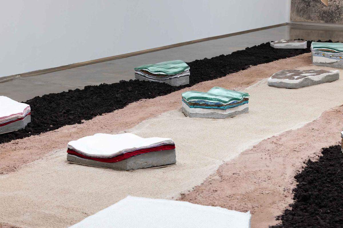Instalación que, un tanto a modo de isla, se expande sobre el suelo de la sala. Esta especie de isla fue realizada concéntricamente con tres materiales de distintos colores.
