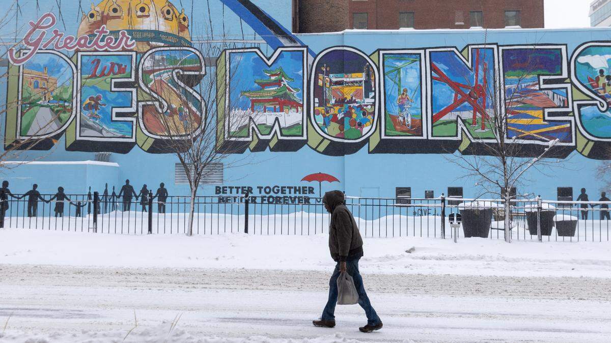 Un hombre camina durante una tormenta de nieve el viernes 12 de enero de 2024 frente a un mural de Des Moines, la capital de Iowa. El estado organiza un caucus (asamblea electoral) que da comienzo a las primarias republicanas el lunes 15 de enero de 2024.