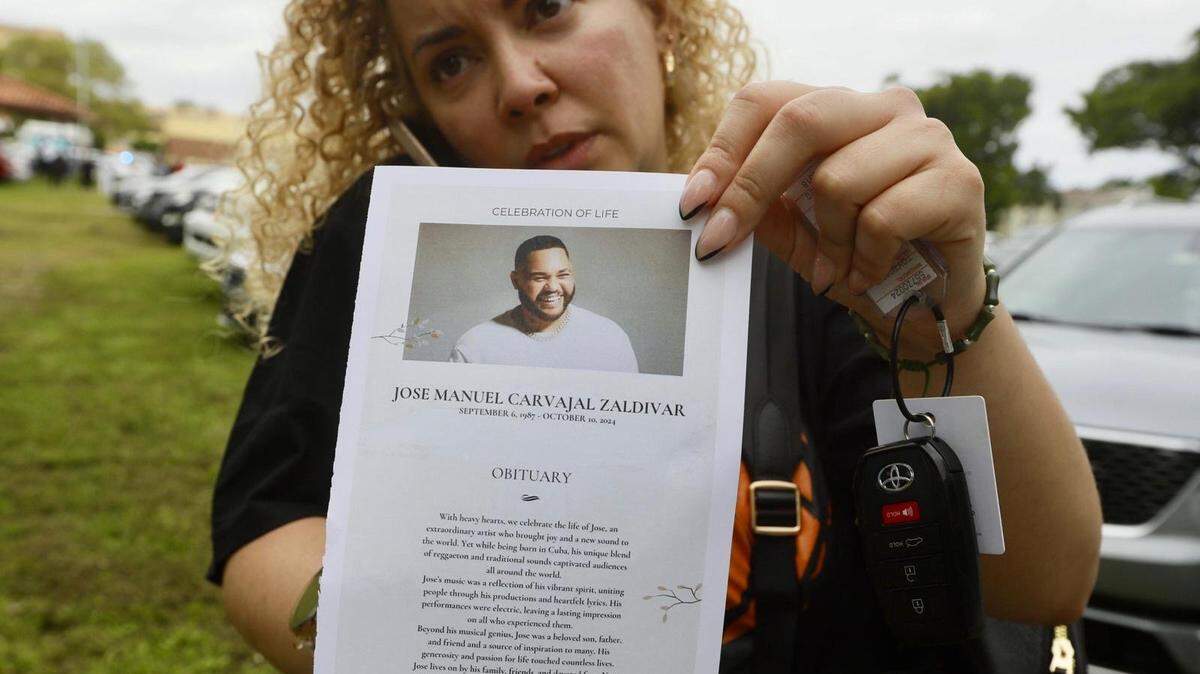 El 19 de octubre de 2024, Adis Martinez, una fanática del reguetonero cubano El Taiger, muestra una imagen del artista en las afueras de la Iglesia Católica de San Lázaro en Hialeah, donde se rindieron honras fúnebres al artista presuntamente asesinado por Damián Valdez Galloso.