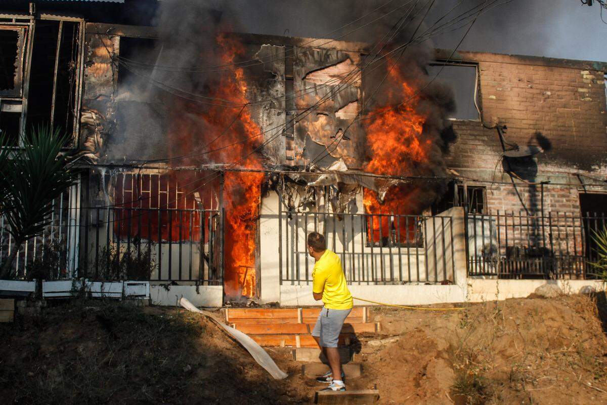 Una persona trata de apagar las llamas que consumen su casa, cerca del gran incendio en el sector de Viña del Mar, Chile, que ha afectado al menos 3,000 casas, el sábado 3 de febrero de 2024.