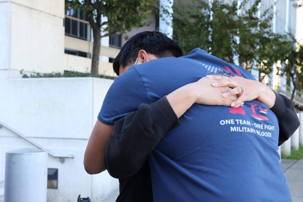 Julio Peña Jr. abraza a su madrastra, Lydia Romero, afuera de un centro de detención de inmigrantes en el centro de Los Ángeles mientras intentan obtener información sobre su padre, Julio César Peña, quien fue detenido por el ICE en diciembre.