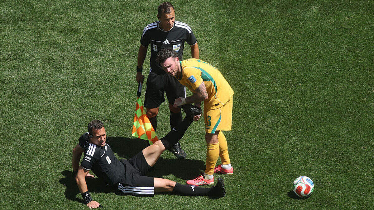 El mediocampista australiano Aiden O’Neill ayuda al árbitro alemán Felix Zwayer, quien sufrió un fuerte calambre en la pierna izquierda en los minutos finales del partido entre Estados Unidos y Australia, el 19 de junio de 2026 en Seattle, Estados Unidos.