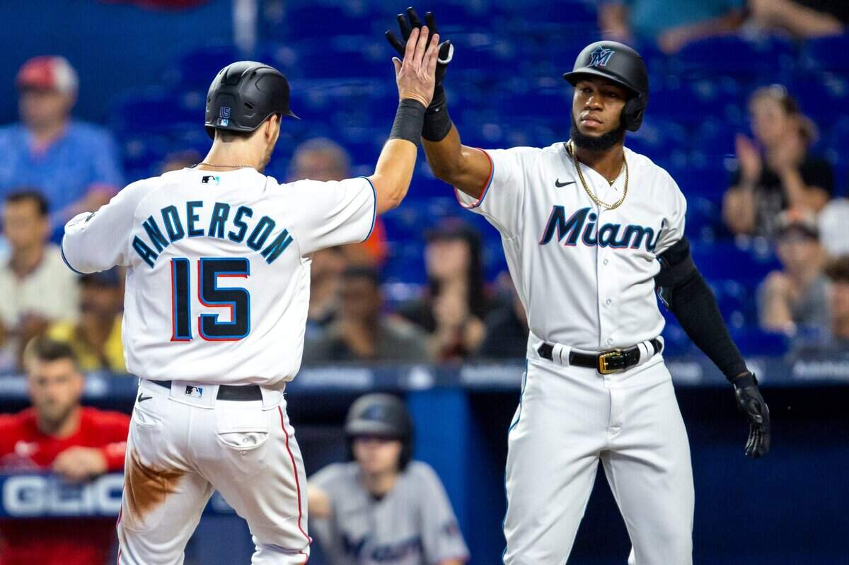Brian Anderson (izq.) recibe el saludo de Bryan De La Cruz tras anotar una carrera para los Marlins en el tercer inning del partido ante los Filis de Filadelfia, el 17 de abril de 2022 en Miami.