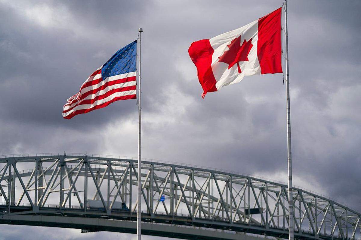 The US and Canada flags flutter next to the Blue Water Bridge border crossing in Point Edward, Ontario, on October 24, 2025. US President Donald Trump said October 23, 2025 he was ending trade talks with Canada over an anti-tariff advertising campaign, a sudden about-face soon after a cordial White House meeting with Prime Minister Mark Carney. On his Truth Social network, Trump vented fury at what he called a "fake" ad that he said misquoted former president Ronald Reagan discussing tariff policy. (Photo by Geoff Robins / AFP) (Photo by GEOFF ROBINS/AFP via Getty Images)