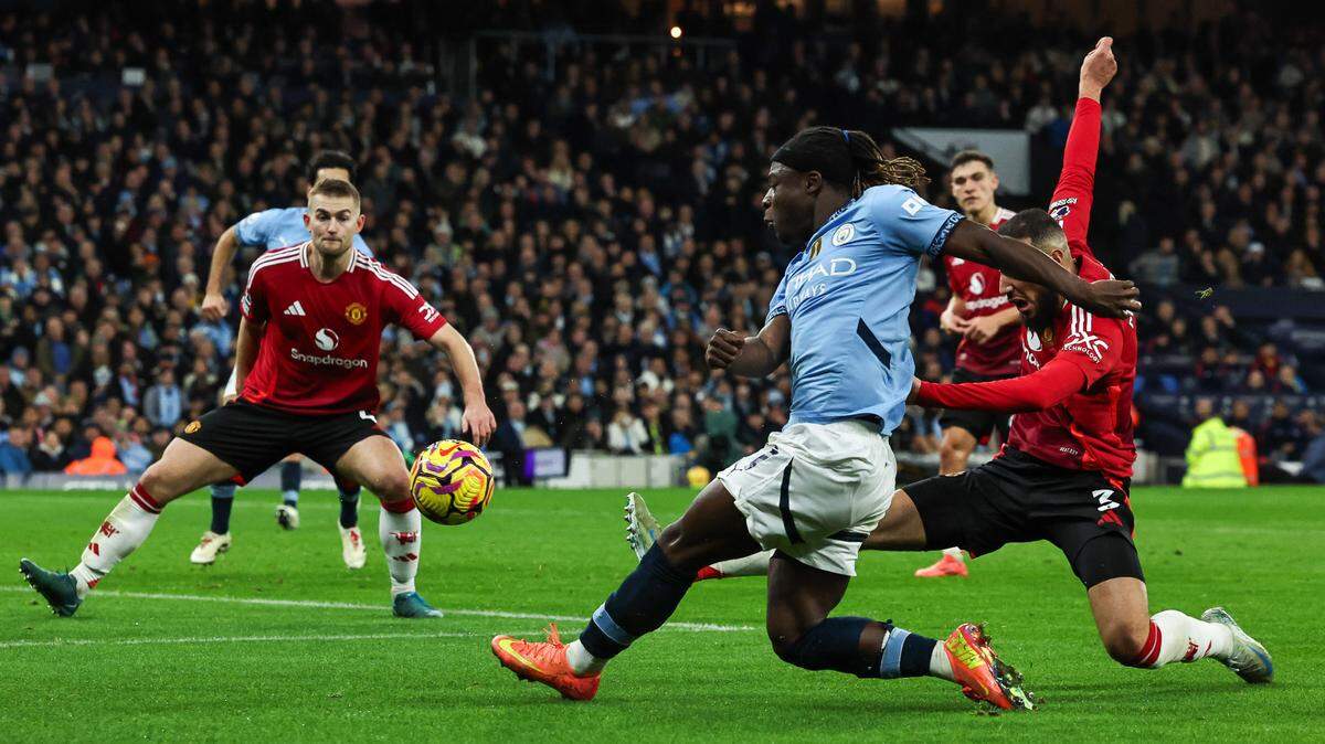 El jugador del Manchester City Doku (centro) patea la pelota ante la defensa del Manchester United, en el partido celebrado el 15 de diciembre de 2024 en el Etihad Stadium, en Manchester.