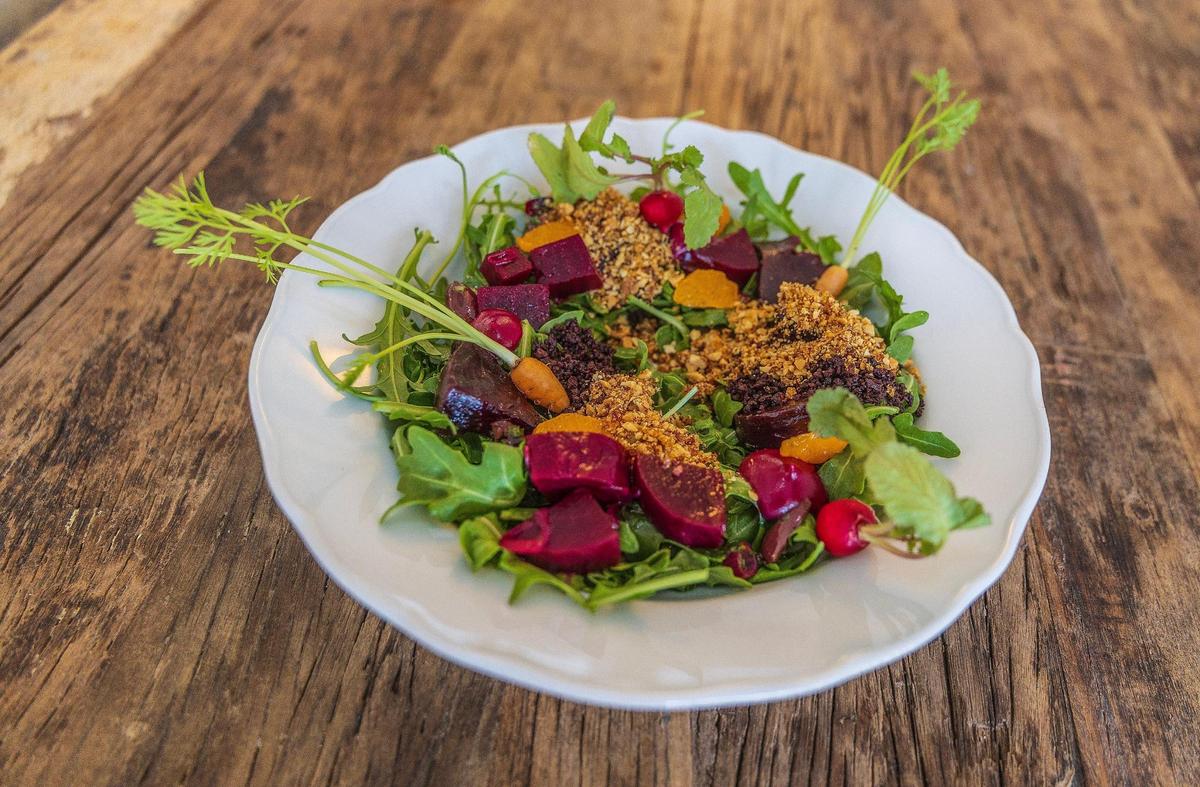 La ensalada de remolacha triple de Mutra incluye tzatziki vegano, remolacha encurtida, remolacha a la parrilla, crema de remolacha, clementina flameada, salsa chermoula, rúcula, rábanos pequeños, polvo de kalamata y almendras garrapiñadas.