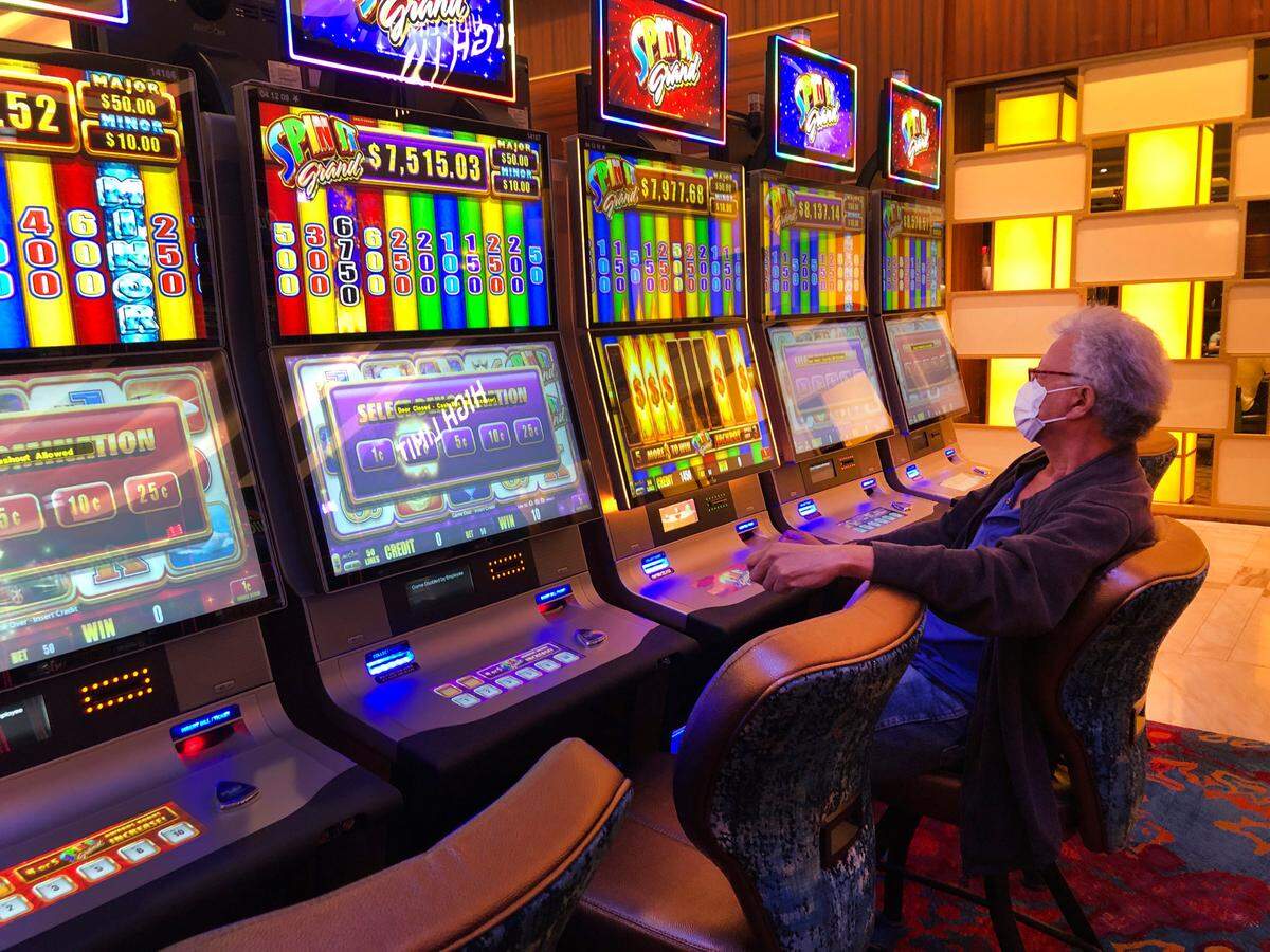 A patron wearing a mask plays a slot machine at the Seminole Hard Rock Hotel & Casino, Friday, March 20, 2020, near Hollywood, Fla.
