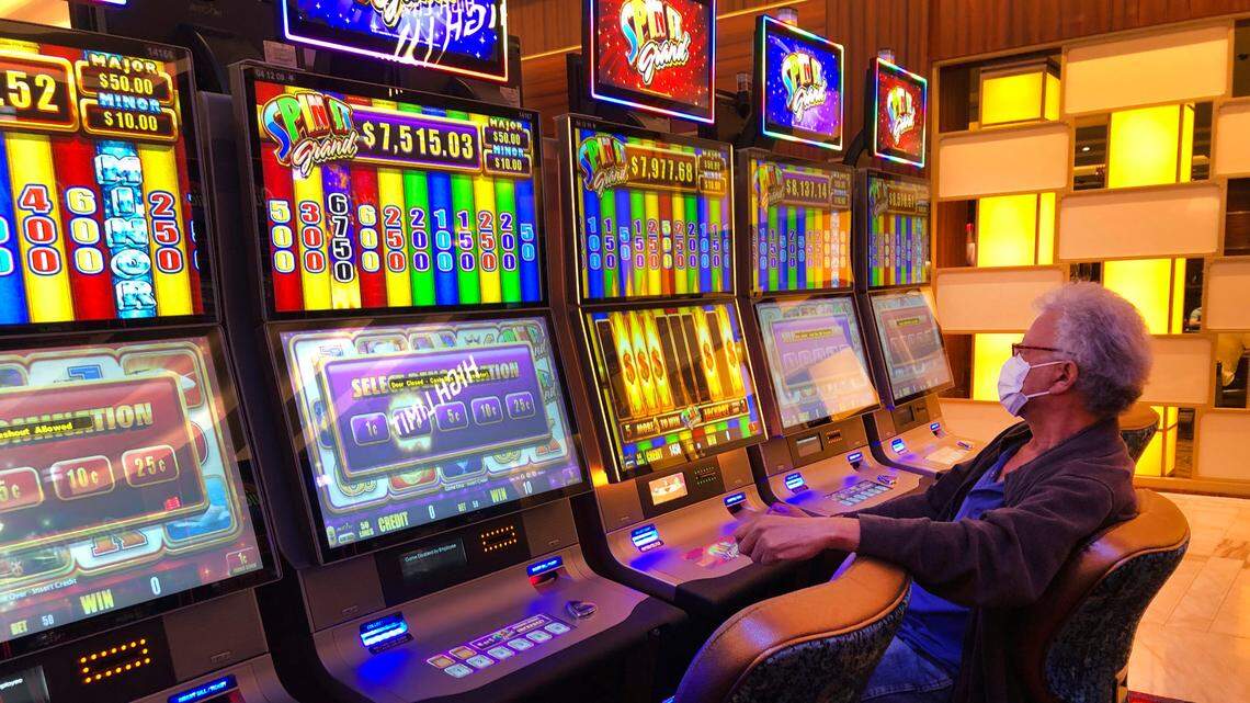 A patron wearing a mask, plays a slot machine at the Seminole Hard Rock Hotel & Casino, Friday, March 20, 2020, near Hollywood, Fla.