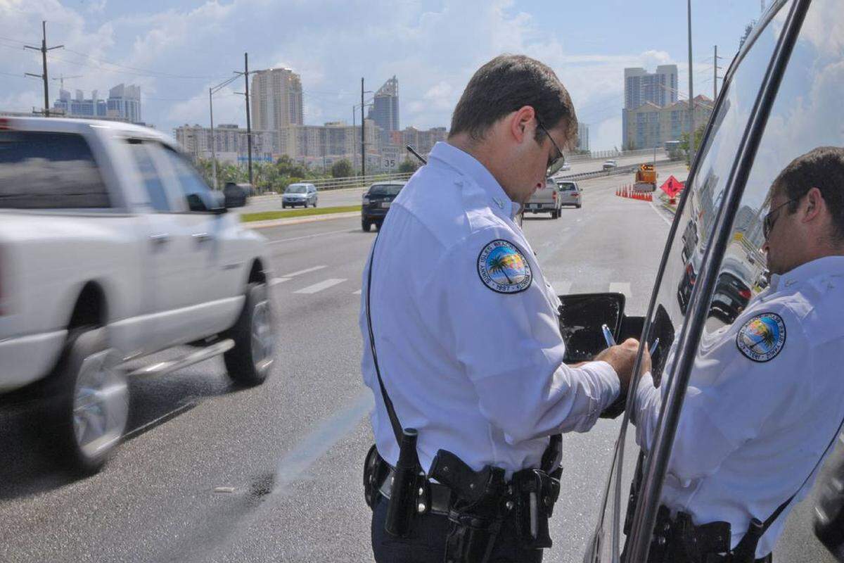 En esta foto de archivo del 12 de junio de 2008, el agente de policía de Sunny Isles Beach, Ricky Reffitt, multa a un conductor que infringió la Ley de Cambiar de Senda en la Florida. La ley se amplió en 2024.