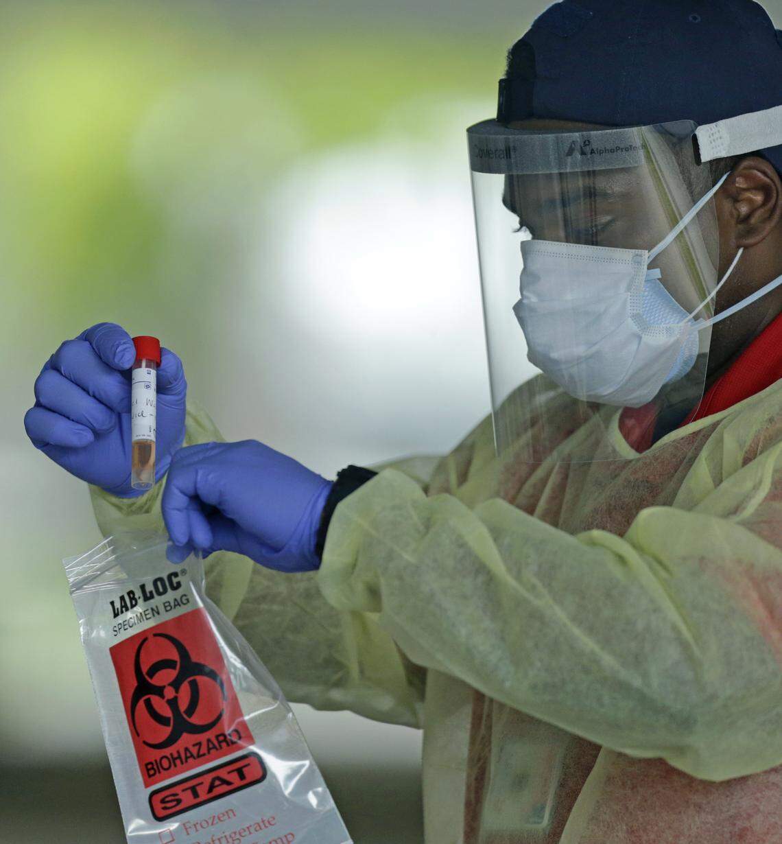 An American Medical Response health worker holds a swab tests from citizens after being tested at the COVID-19 drive-thru testing center at Holiday Park located at 1150 G. Harold Martin Drive in Fort Lauderdale as the coronavirus pandemic continues on Thursday, April 30, 2020.