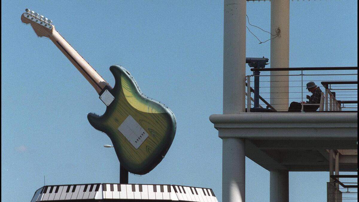 Un hombre almuerza contemplando la guitarra situada en la azotea del Hard Rock Cafe en 1998. La guitarra es una réplica de una Fender Stratocaster de 1957, construida a una escala 22 veces mayor que su tamaño original.