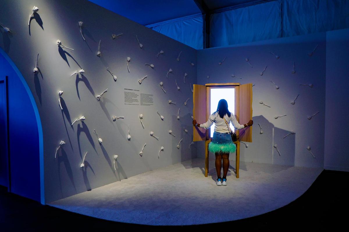 Rhea King observa un cielo incrustado en un gabinete de madera tallada con el telón de fondo de la instalación “Flower Season” del artista Mathieu Lehanneur mientras la feria celebra su vigésima edición con el tema principal de ‘Blue Sky: una celebración de saltos audaces en el diseño’ en Design Miami en Miami Beach, Florida, el martes 3 de diciembre de 2024. 2024.