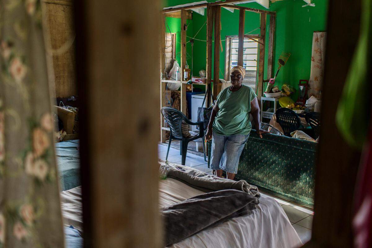 Un toldo blanco todavía cubre una sección de la casa de color amarillo brillante donde vive Helen Penn, de 74 años, con sus dos hijos. Aún no hay muros interiores en la casa. Sin electricidad, la familia depende de pequeñas lámparas solares durante la noche.