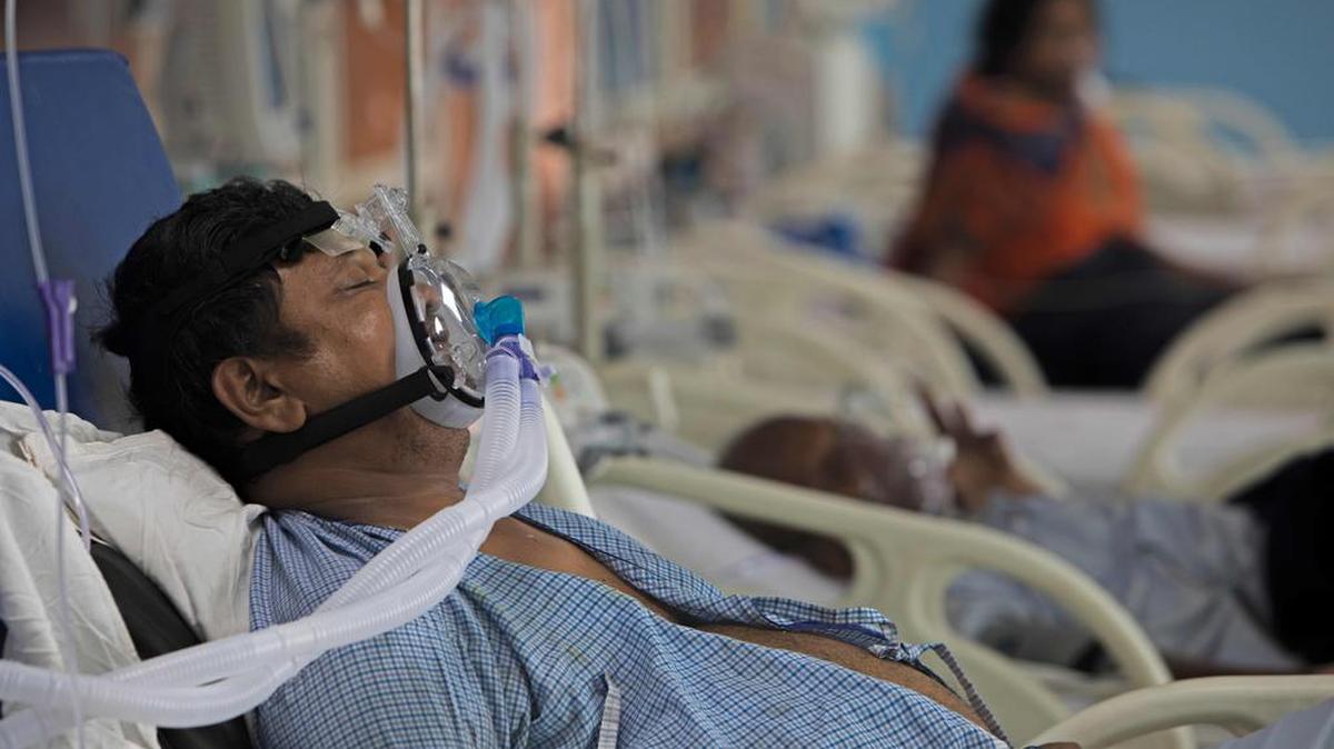 En esta fotografía tomada el 15 de julio de 2020, un paciente con coronavirus COVID-19 yace en una cama en la Unidad de Cuidados Intensivos del Hospital Sharda, en Greater Noida. - Dentro de una unidad de cuidados intensivos de la India sin aire acondicionado, el doctor Showkat Nazir Wani está arriesgando su vida luchando contra el calor brutal y tratando a pacientes con coronavirus.