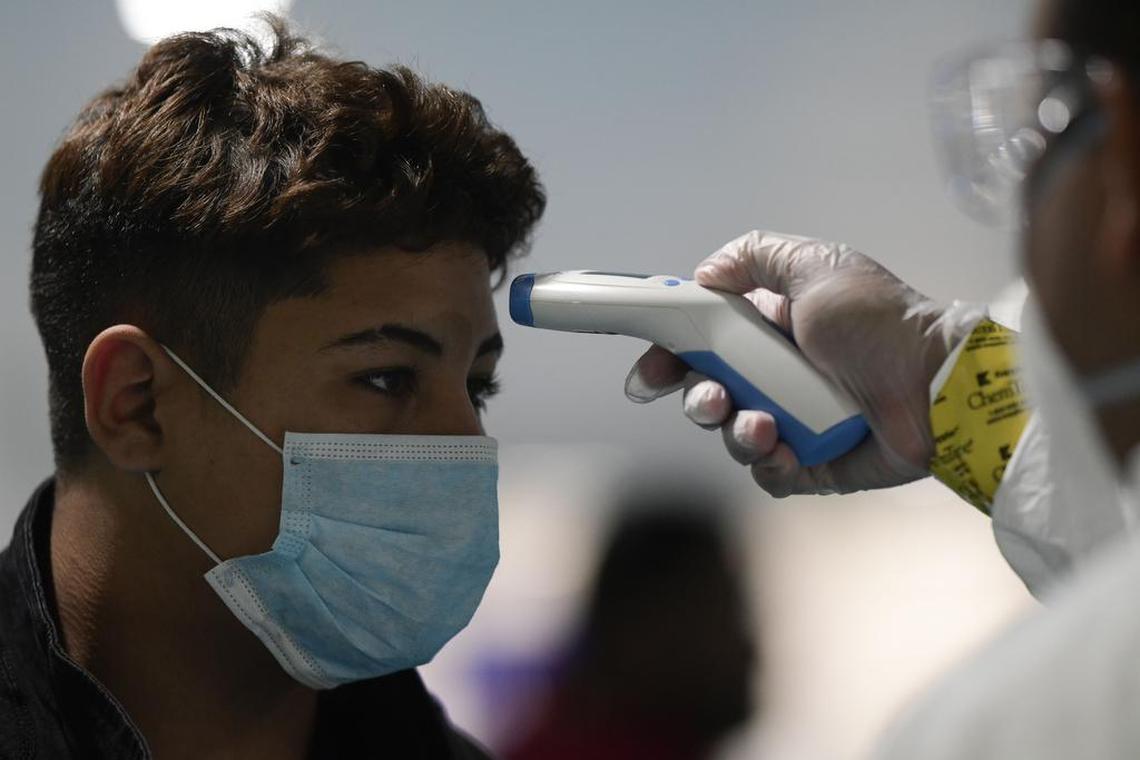 National Guard staff check a passenger’s temperature at Luis Muñoz Marín Airport in Carolina, Puerto Rico, on Tuesday, March 17, 2020.