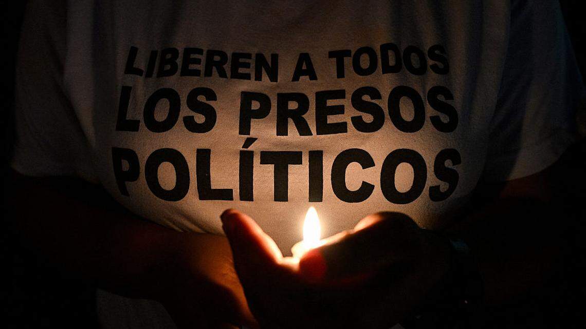 Una persona que viste una camiseta que dice “Liberen a todos los presos políticos” enciende una vela durante una vigilia frente a la prisión El Rodeo I en Guatire, estado Miranda, Venezuela, el 23 de febrero de 2026.