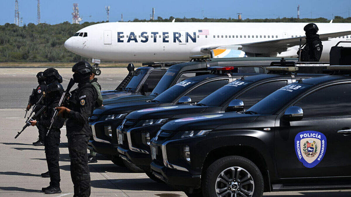 Agentes de la Policía Nacional Bolivariana montan guardia mientras un avión de Eastern Airlines que transporta migrantes venezolanos deportados de Estados Unidos aterriza en el Aeropuerto Internacional Simón Bolívar en Maiquetía, Venezuela, el 16 de enero de 2026.