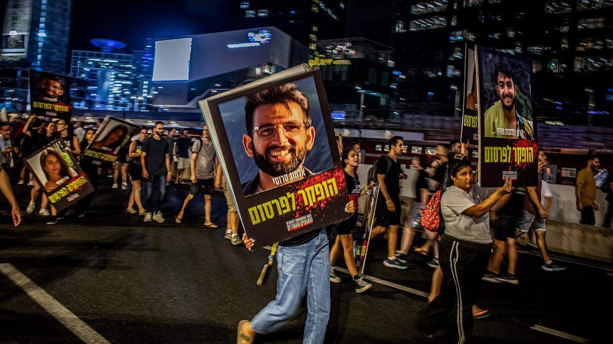 Manifestantes caminan con retratos de ciudadanos israelíes capturados como rehenes por el grupo islamista Hamás, durante una protesta el domingo 1 de septiembre de 2024 en Tel Avid, Israel.
