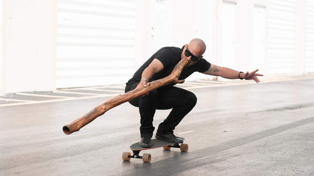 Michael Gil transporta un instrumento ancestral australiano en una patineta.