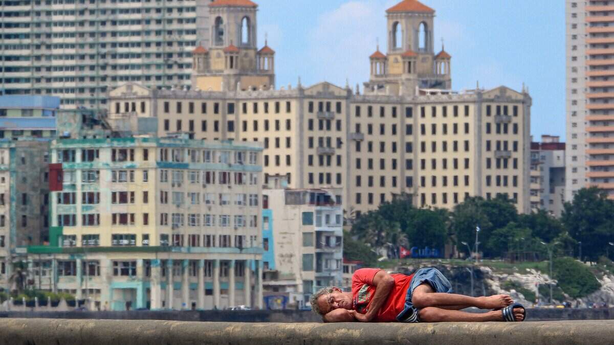 A man sleeps on Havana's Malecon waterfront on October 2, 2025. Poverty levels have risen sharply as Cuba faces its worst economic crisis in three decades, characterized by severe shortages of food, medicine, and fuel, along with daily power outages. (Photo by ADALBERTO ROQUE / AFP) (Photo by ADALBERTO ROQUE/AFP via Getty Images)          