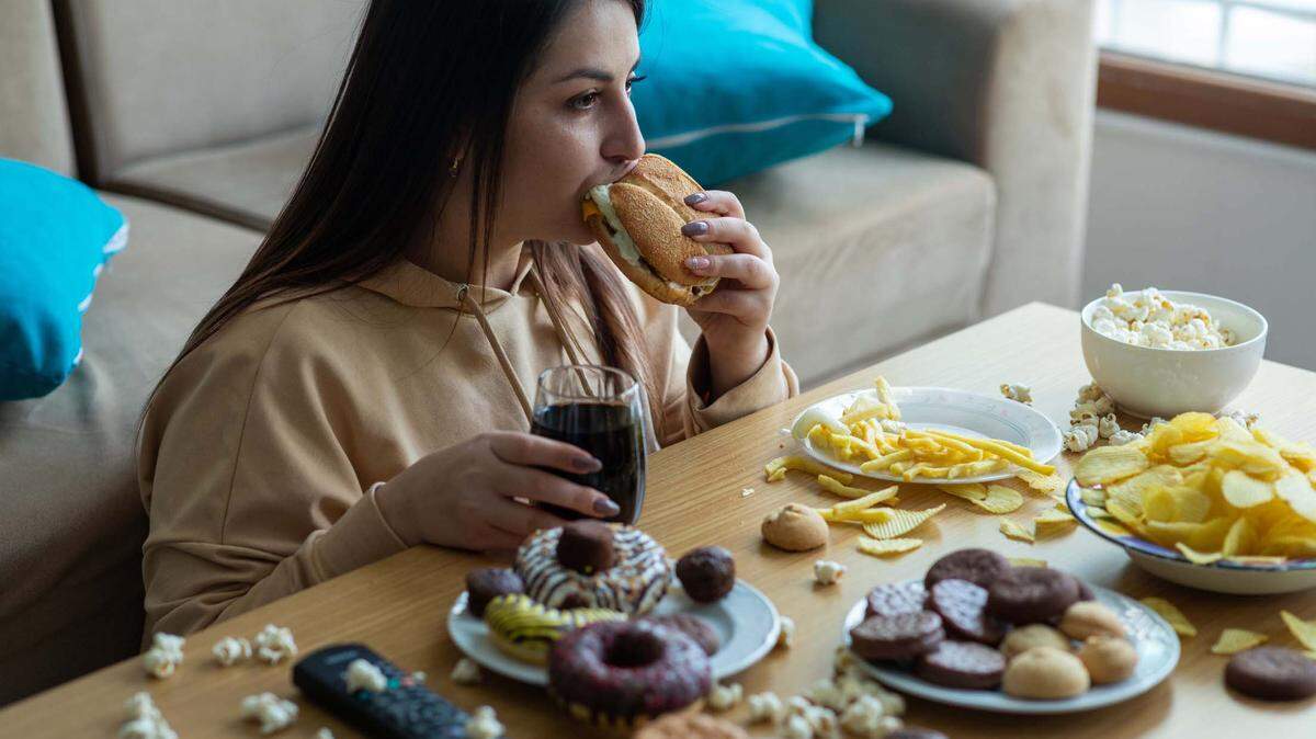 Mujer joven con sobrepeso comiendo comida chatarra.