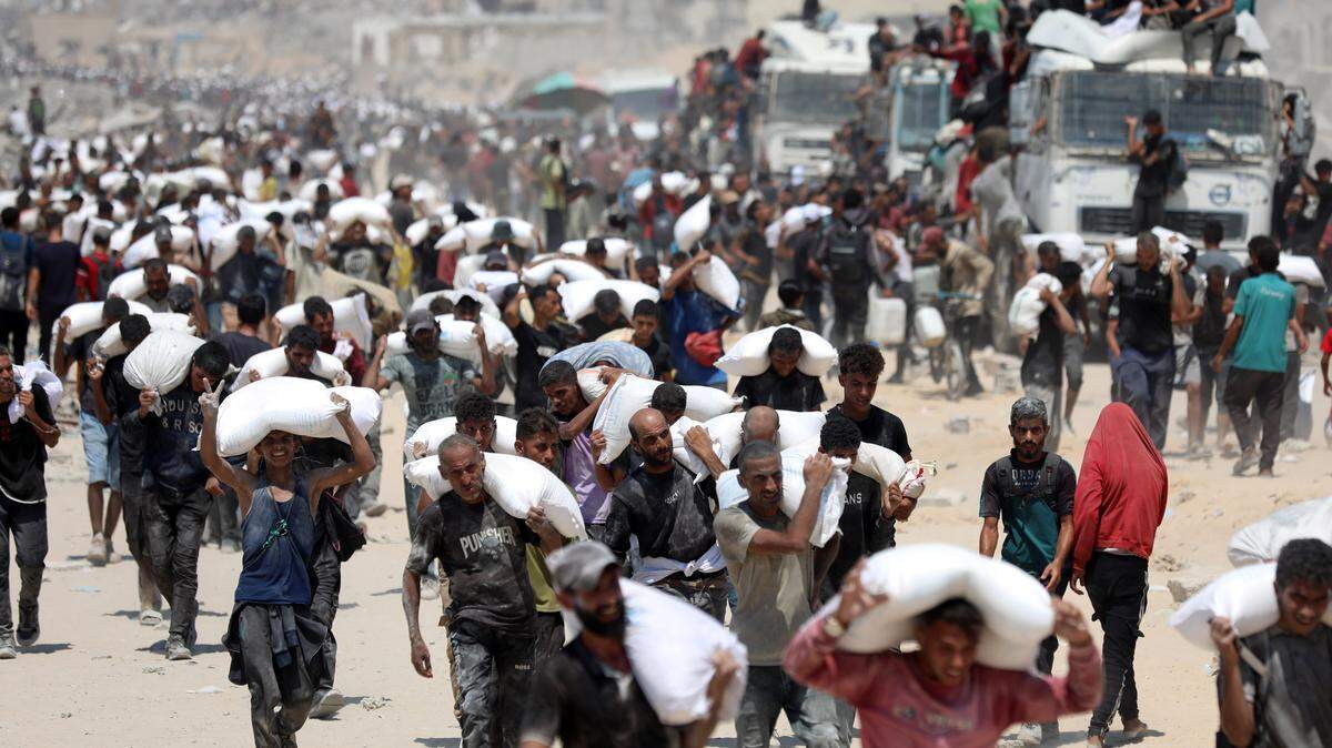 Palestinos cargan sacos de harina luego de que la ayuda humanitaria ingresara a Gaza a través de un cruce fronterizo, en Beit Lahia, el 27 de julio de 2025.