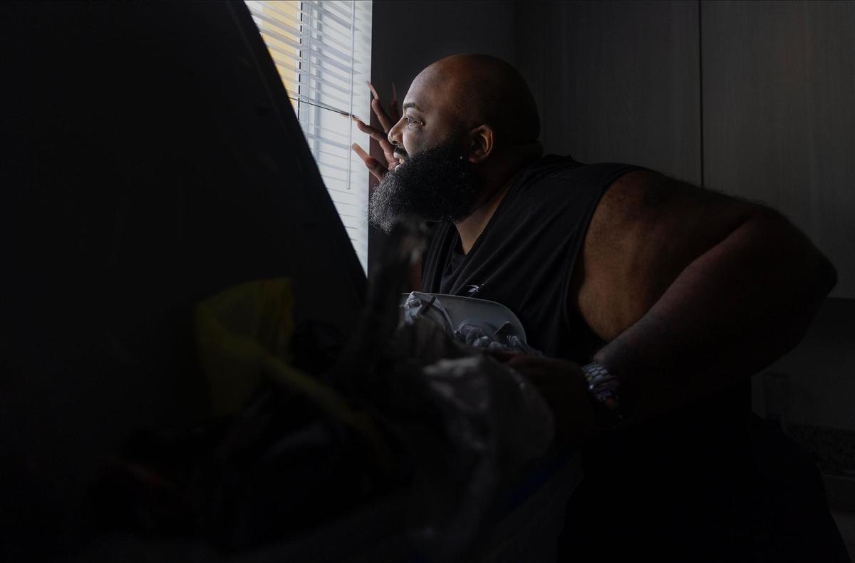 Christopher Saunders, de 43 años, mira por la ventana y admira la vista desde su apartamento en Wenski Groves. Saunders se mudó al complejo de viviendas asequibles después de tener dificultades para pagar su condominio en North Miami Beach.