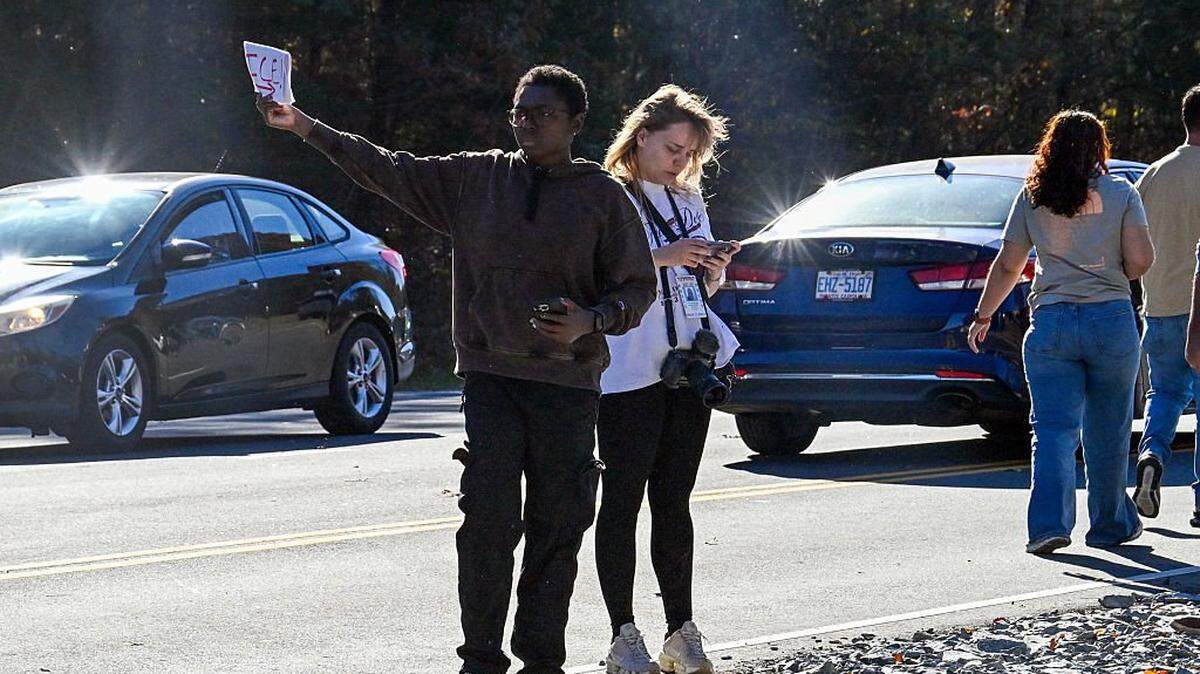 A resident holds up a sign to warn drivers of a possible Immigration and Customs Enforcement (ICE) operation in Charlotte, North Carolina, on November 16, 2025. Federal immigration officers began immigration enforcement operations in Charlotte on November 15, they confirmed in a statement. "We are surging DHS law enforcement to Charlotte to ensure Americans are safe and public safety threats are removed," Assistant Homeland Security Secretary Tricia McLaughlin said. US President Donald Trump has made deporting undocumented immigrants a key priority for his second term, after successfully campaigning against an alleged "invasion" by criminals. (Photo by Peter Zay / AFP) (Photo by PETER ZAY/AFP via Getty Images)
