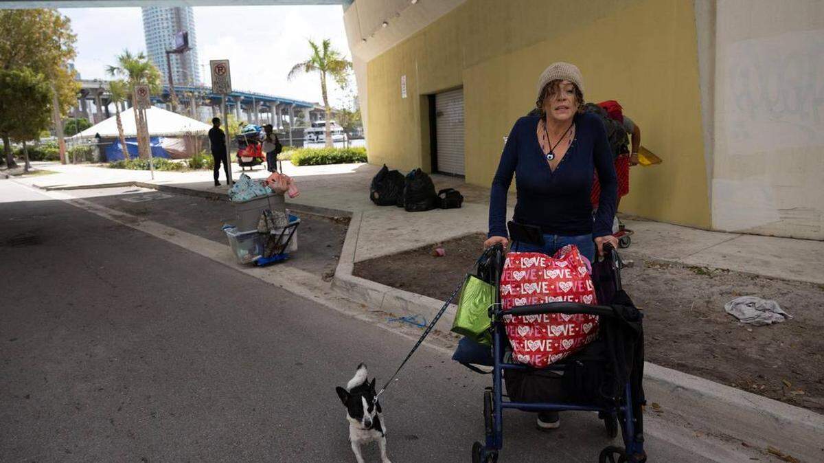 Eli, veterana de guerra, camina con su perro después que ella y su compañero empacaron sus pertenencias cuando la policía de Miami los obligó a abandonar el área el jueves, 29 de febrero de 2024, en el downtown de Miami.