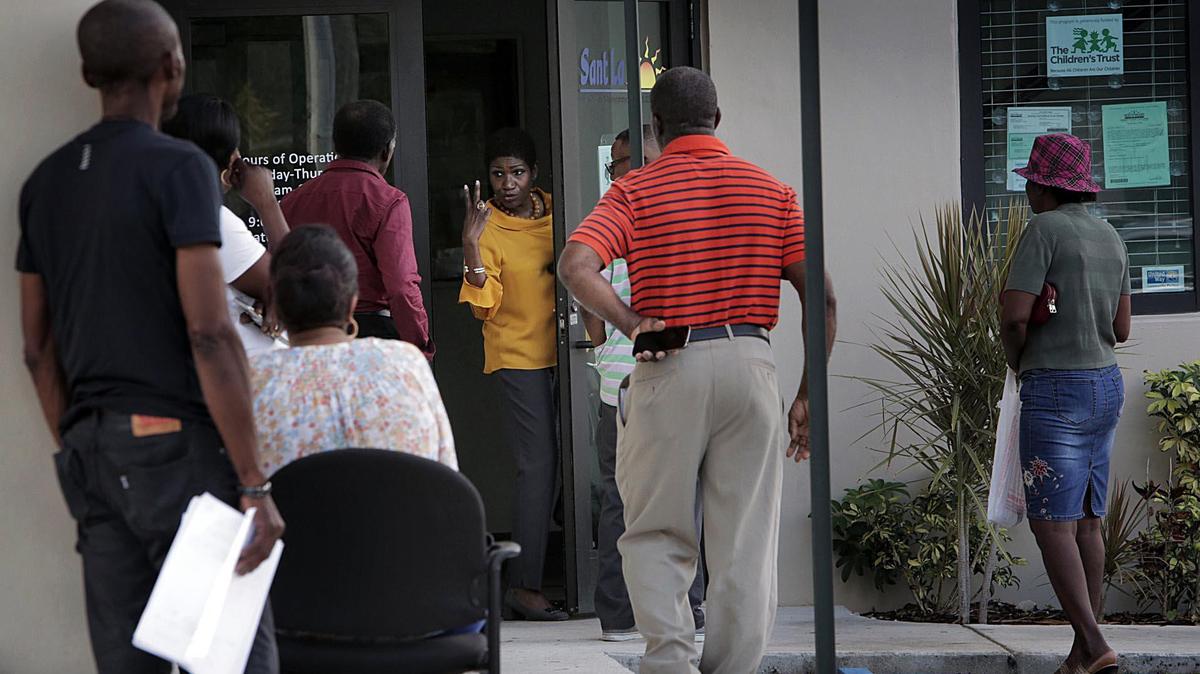 Gepsie Metellus, directora de Sant La Haitian Neighborhood Center (al centro, indica cómo mantener la distancia durante el coronavirus a las personas que esperan para solicitar ayuda por desempleo.