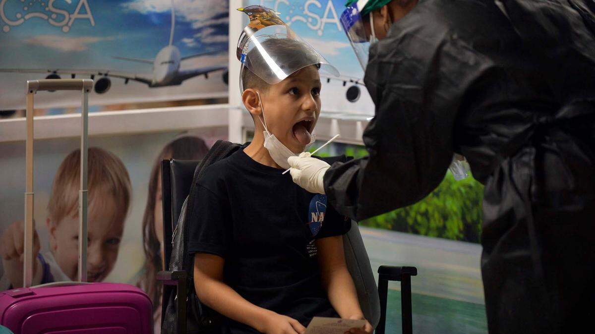 Un trabajador médico recoge muestras de hisopos de un niño que llegó al Aeropuerto Internacional José Martí en La Habana, Cuba, 15 de noviembre de 2020. 