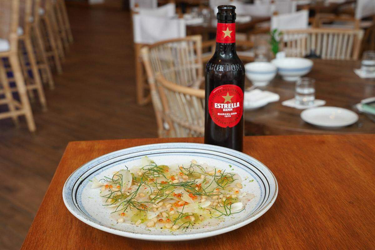 De aperitivo Heaven Mykonos ofrece carpacho de pez espada crudo en rodajas finas, uvas verdes, frentes de hinojo y huevas de trucha ahumada.