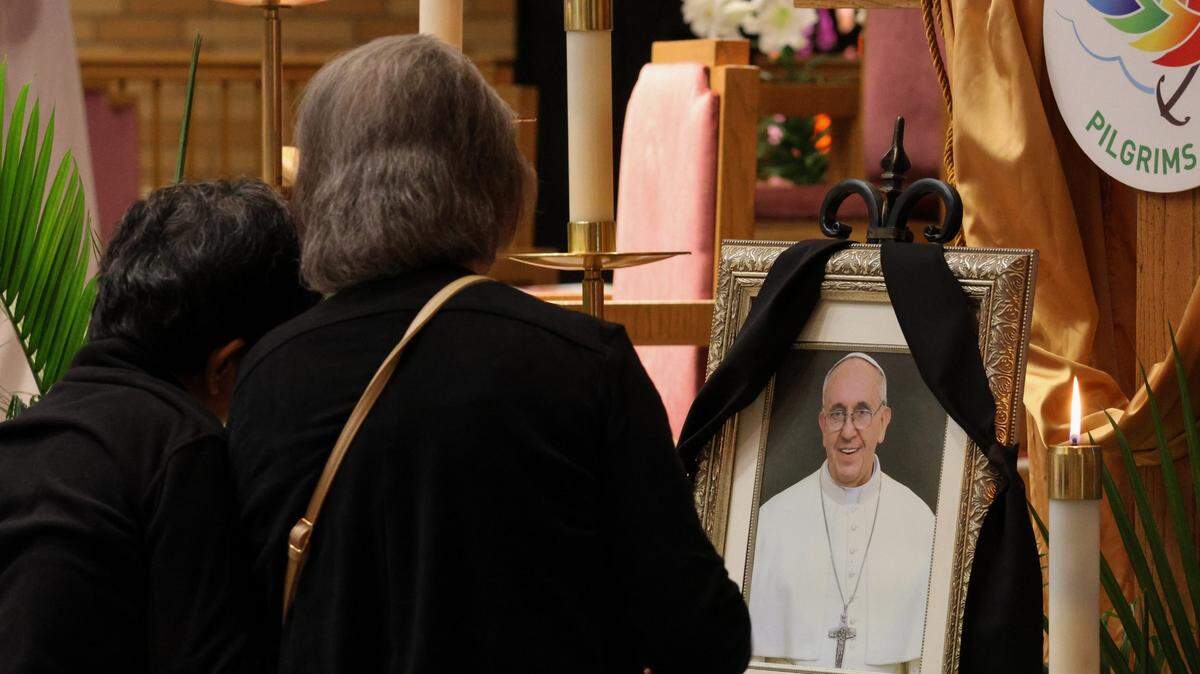 Worshipers pause at the portrait of Pope Francis following a special Mass to honor Pope Francis on Saturday, April 26, 2025 at Christ the King Cathedral in Lubbock, Texas.