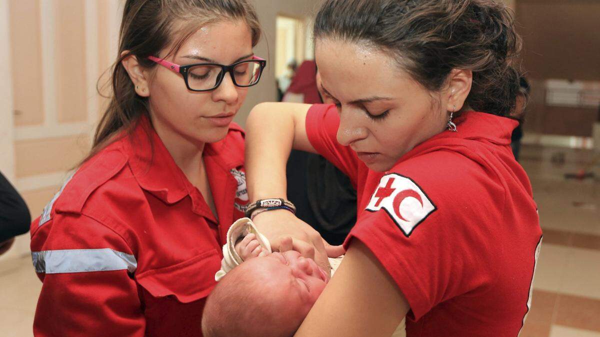Voluntarios del Comité Internacional de la Cruz Roja (CICR) comprobando el estado de salud de un bebé en Muadamiya al Sham (suroeste de Damasco). La decisión de Estados Unidos de abandonar la Organización Mundial de la Salud (OMS) puede condicionar muchos de los programas de cooperación internacional.