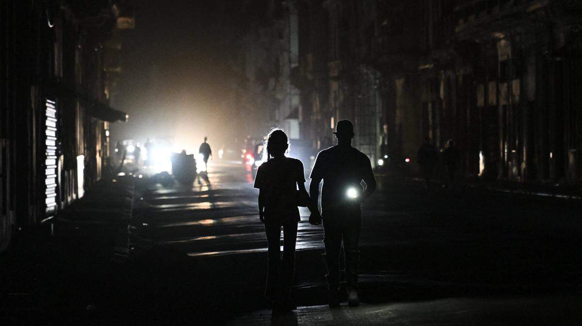 Personas caminan por una calle sin electricidad durante un apagón nacional en La Habana el 21 de marzo de 2026.