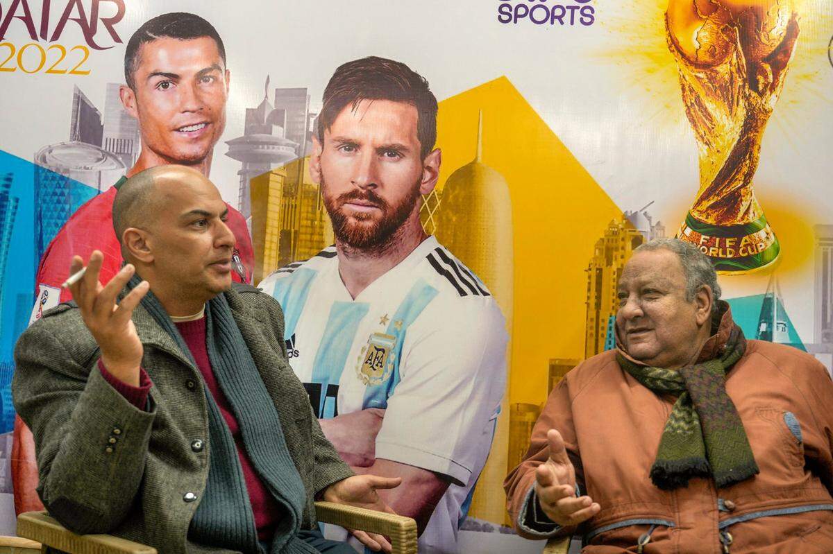 Foto de archivo. Dos personas conversan frente a un cartel que muestra a Lionel Messi (der.) y Cristiano Ronaldo en una cafetería en El Cairo, Egipto, el 14 de enero de 2023.