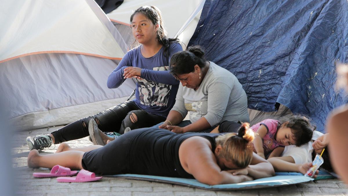 Una familia migrante espera en el lado de Matamoros, a la entrada del Puente Internacional. Muchos migrantes que no pueden pagar el alquiler de habitaciones se quedan en este campamento improvisado mientras esperan pedir asilo en Estados Unidos.