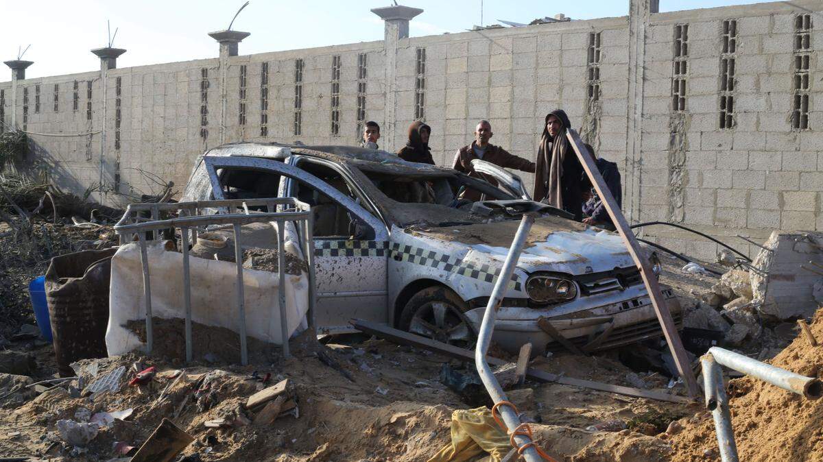 Varias personas revisan un auto destruido por un bombardeo israelí en Rafah, en el sur de la Franja de Gaza, el domingo 18 de febrero de 2024.