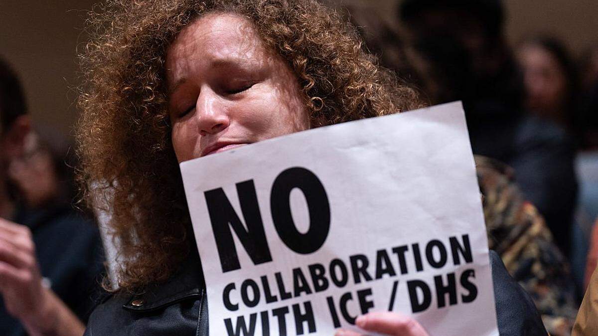 An anti-ICE and Border Patrol protestor cries as they hold a sign before being removed from City Hall by New Orleans Police Department officers after protestors disrupted a city council meeting in New Orleans, Louisiana, on December 4, 2025. The US Department of Homeland Security announced on December 3 it has launched a federal immigration enforcement operation, named "Operation Catahoula Crunch," in the New Orleans, Louisiana, area. (Photo by Adam GRAY / AFP via Getty Images)