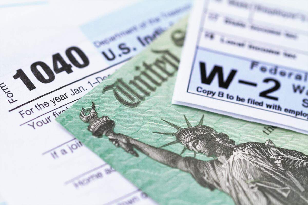 Formulario de impuesto sobre la renta 1040 y declaración de salario w-2 con un cheque de reembolso del Departamento del Tesoro.