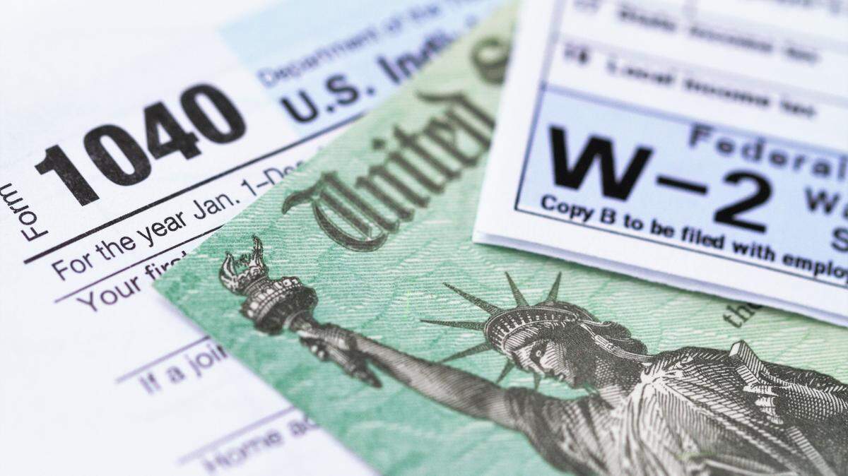 Formulario de impuesto sobre la renta 1040 y declaración de salario w-2 con un cheque de reembolso del Departamento del Tesoro.