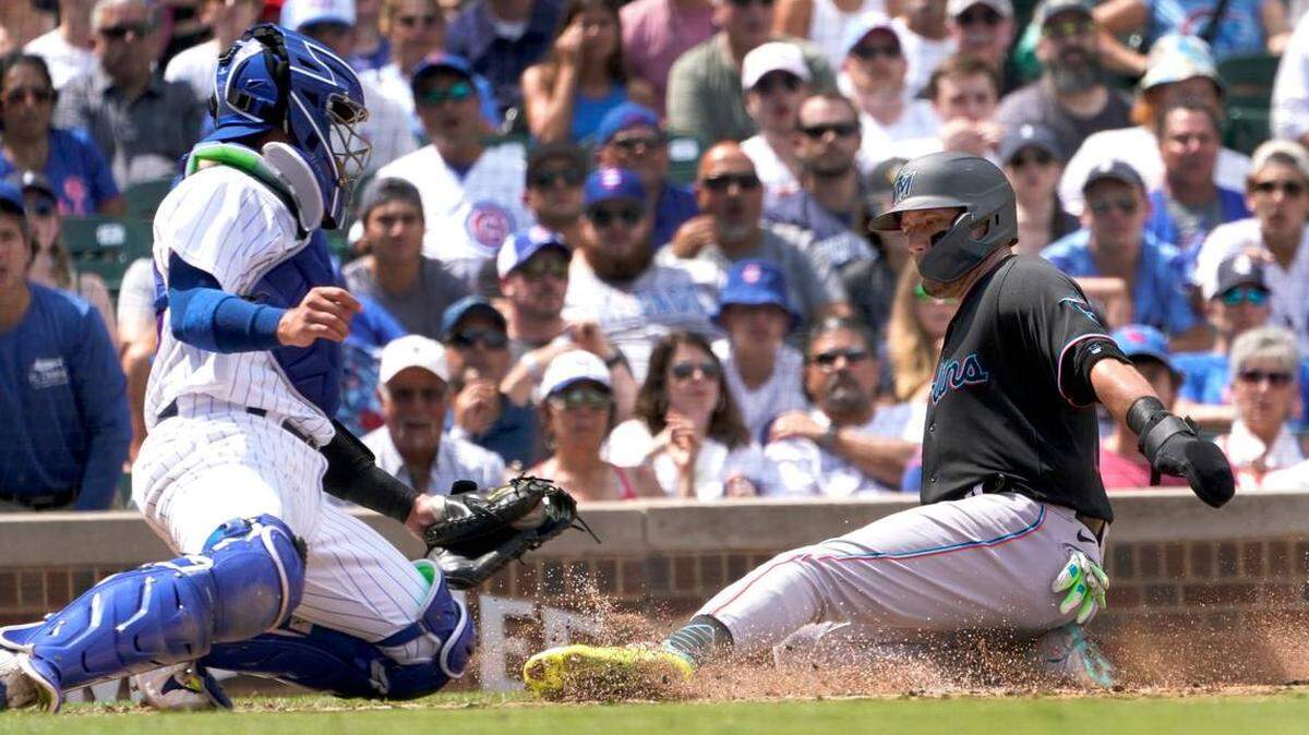El receptor de los Cachorros, P.J. Higgins, a la izquierda, pone out a Miguel Rojas de los Marlins de Miami en casa durante la tercera entrada de un juego de béisbol el sábado 6 de agosto de 2022 en Chicago.