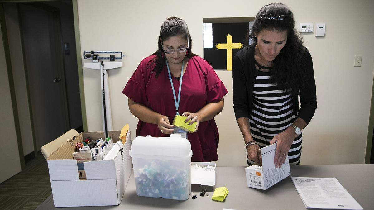 Rachel Flossie (izq.), enfermera de salud pública del condado de Summit, y Tracy Rodriguez, supervisora de enfermedades transmisibles, se preparan para administrar la vacuna contra la hepatitis A durante el programa de South Street Ministries en Akron, Ohio, en julio. A la sombra de la epidemia de opioides, la hepatitis A se está expandiendo en más de la mitad de los estados, incluyendo Ohio. “”Está llegando al público en general”, dijo Rodríguez. “Da miedo”.