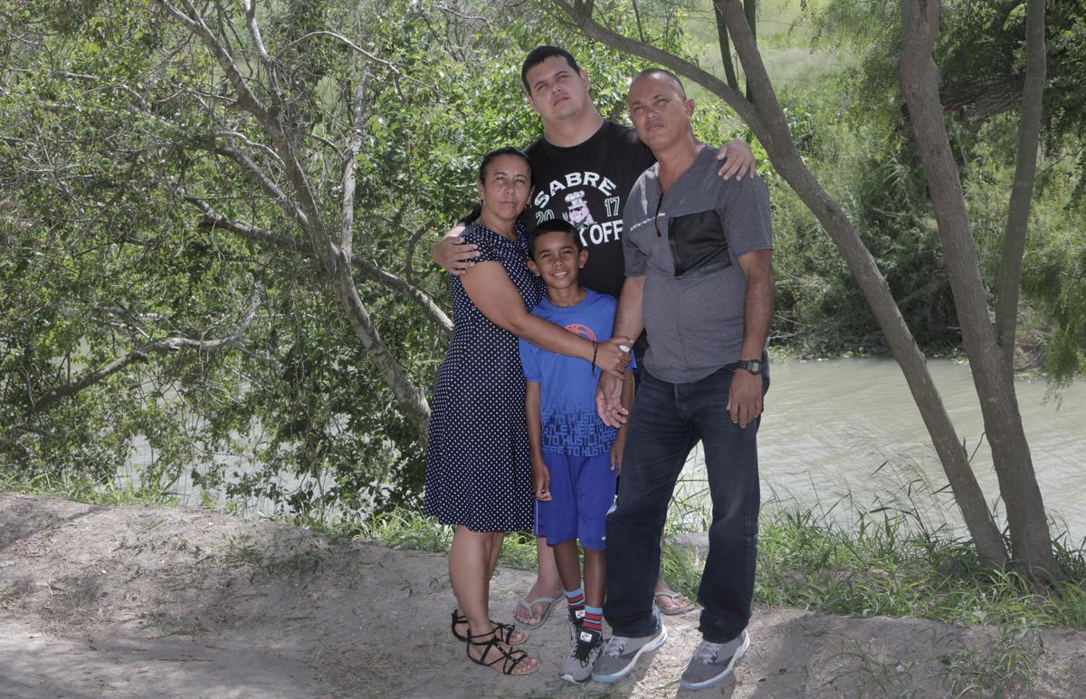 En el sentido de las agujas del reloj de izquierda a derecha: Mairen Barbara Almora, Abel Aguilar Almora, 21 años, Abel Aguilar Columbie, Sergio Almora, 9 años posan para una foto junto al río Bravo en el lado mexicano de la frontera.