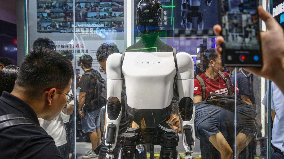 Visitors look at Tesla's humanoid robot Optimus at its exhibition booth during the World Artificial Intelligence Conference (WAIC) in Shanghai on July 5, 2024. (Photo by AFP) / China OUT (Photo by STR/AFP via Getty Images)