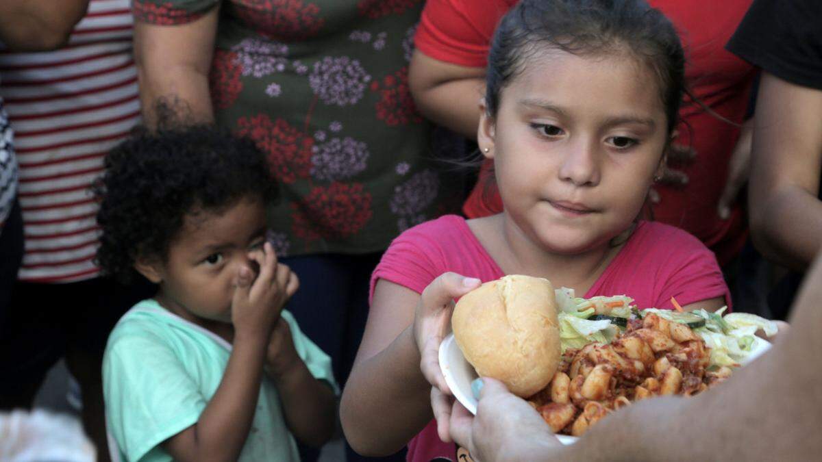 Migrant children line up for food at a migrant camp on the Matamoros, Mexico, side of the Gateway International Bridge that connects Matamoros to Brownsville, Texas.