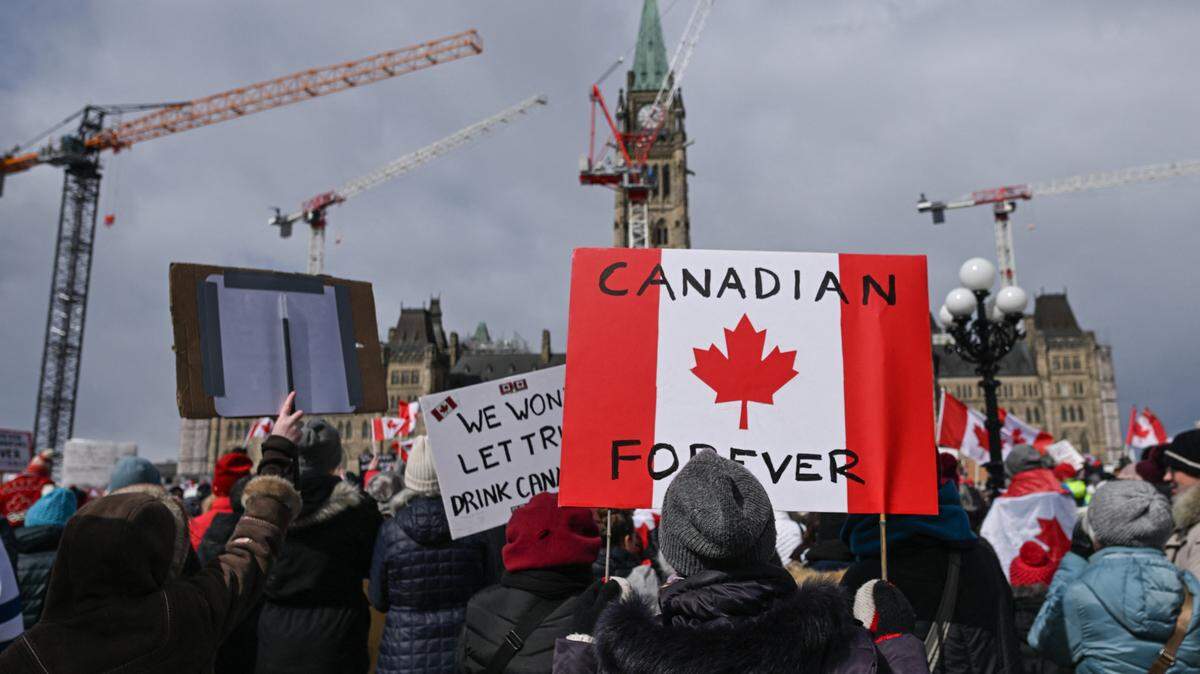 Cientos de personas participan en una manifestación para promocionar unidad y enfatizar la soberanía de Canadá, frente a la sede del Parlamento en Ottawa, el lunes 9 de marzo de 2025. El mensaje en la bandera dice “Canadiense para siempre”.